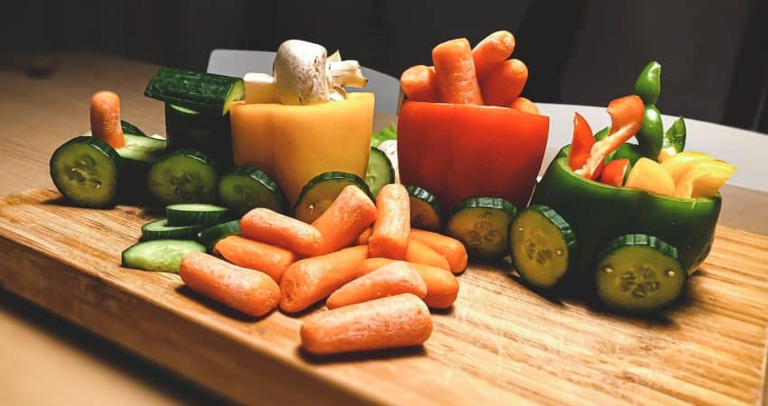 sliced carrots and green bell pepper on brown wooden chopping board